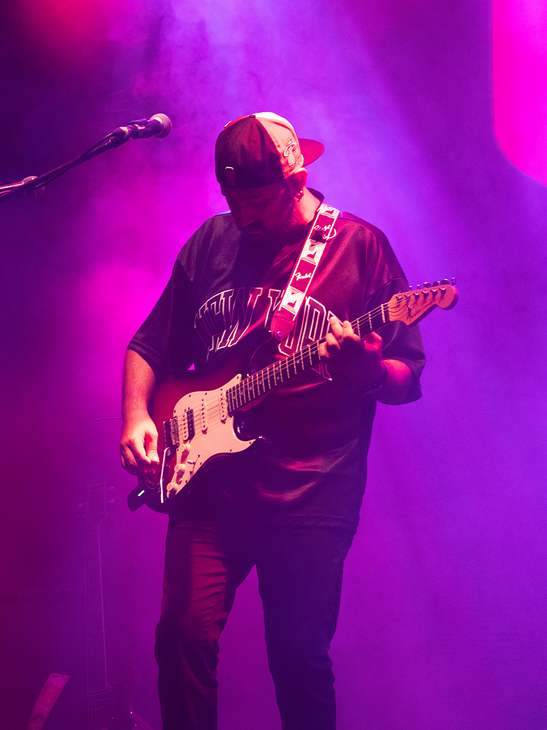 Guitarist performing under purple lights